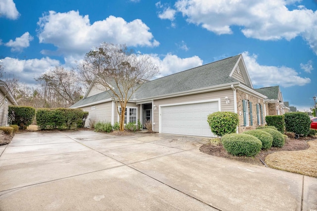 view of front facade featuring an attached garage, a shingled roof, concrete driveway, and brick siding