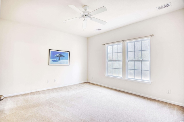 empty room with visible vents, ceiling fan, and light carpet