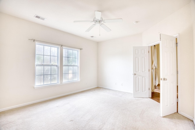 empty room with visible vents, ceiling fan, light carpet, and baseboards