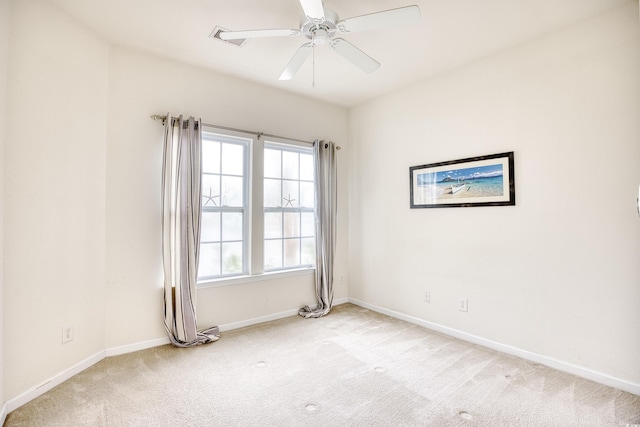 spare room featuring light carpet, a ceiling fan, and baseboards