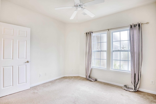 spare room with ceiling fan, baseboards, a wealth of natural light, and light colored carpet