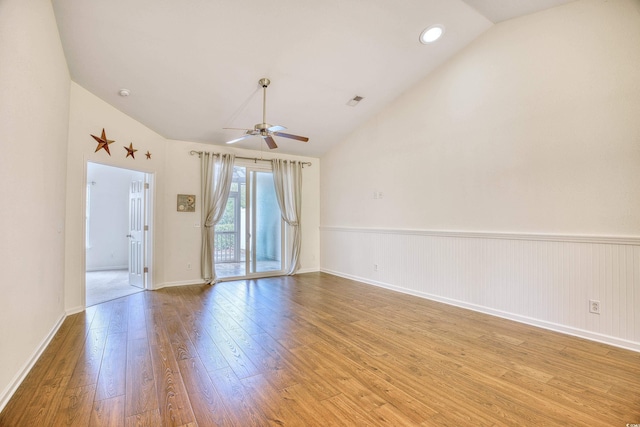 empty room with visible vents, light wood-style flooring, wainscoting, ceiling fan, and high vaulted ceiling