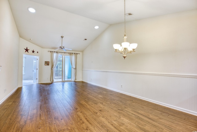 spare room featuring visible vents, wainscoting, hardwood / wood-style floors, vaulted ceiling, and ceiling fan with notable chandelier