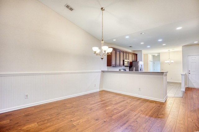 kitchen featuring stainless steel appliances, visible vents, a peninsula, and an inviting chandelier