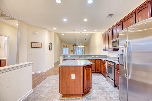 kitchen with a center island, decorative light fixtures, stainless steel appliances, visible vents, and light countertops