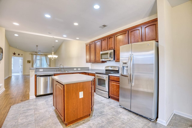 kitchen with appliances with stainless steel finishes, a peninsula, light countertops, pendant lighting, and a sink