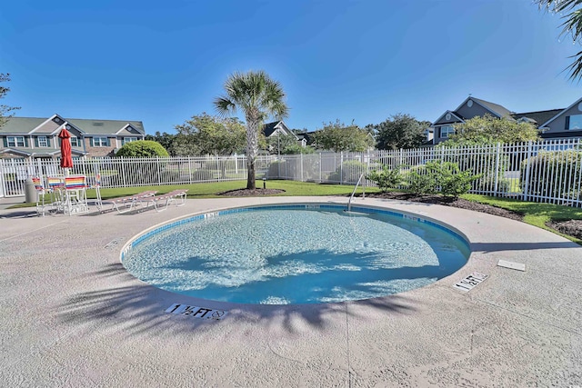 view of swimming pool featuring a patio area, a swimming pool, a residential view, and fence