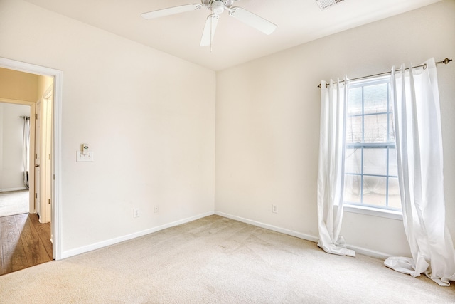 carpeted empty room with ceiling fan, visible vents, and baseboards