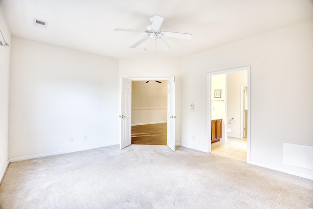 unfurnished bedroom with connected bathroom, light colored carpet, a ceiling fan, baseboards, and visible vents