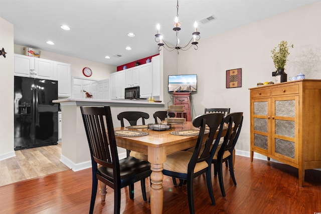 dining room with hardwood / wood-style floors and an inviting chandelier