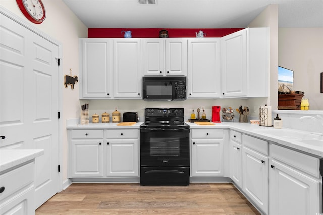 kitchen featuring sink, light hardwood / wood-style flooring, black appliances, and white cabinets