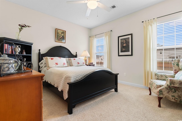 bedroom featuring ceiling fan, light colored carpet, and multiple windows