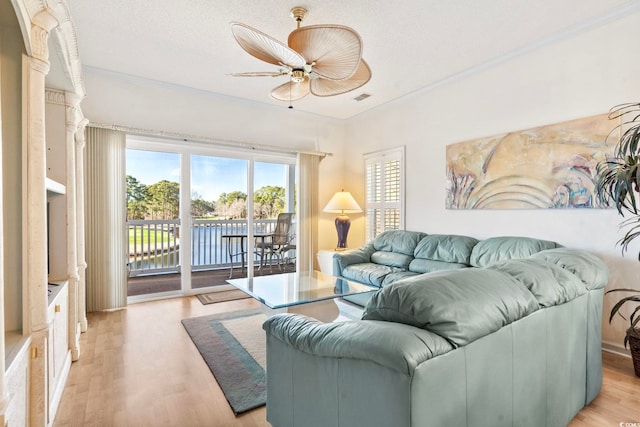 living room with crown molding, ceiling fan, and light wood-type flooring