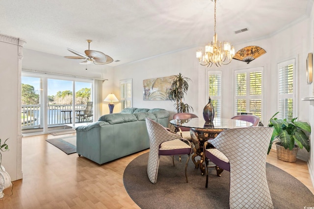 dining room featuring ornamental molding, ceiling fan with notable chandelier, a textured ceiling, and light hardwood / wood-style flooring