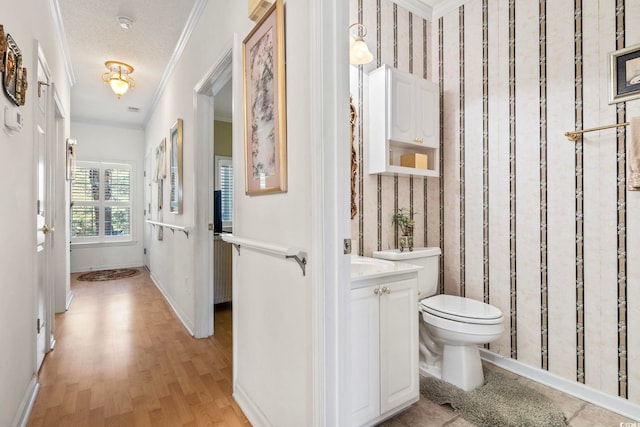 bathroom with hardwood / wood-style flooring, ornamental molding, vanity, toilet, and a textured ceiling