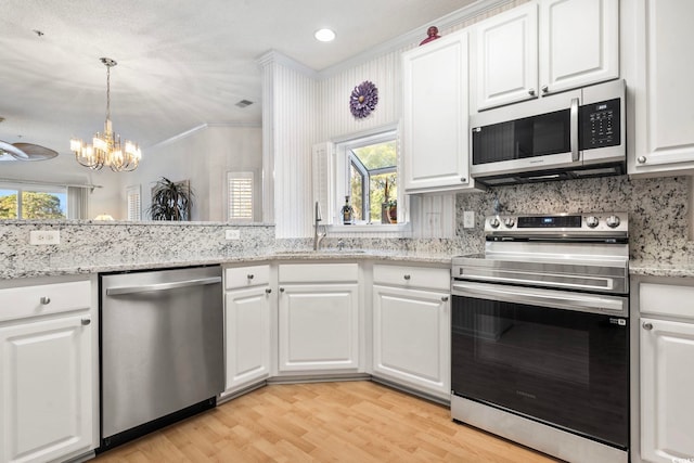 kitchen with sink, decorative light fixtures, appliances with stainless steel finishes, light hardwood / wood-style floors, and white cabinets