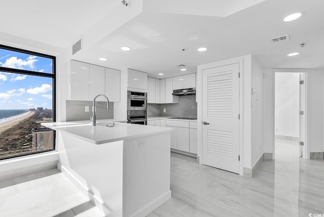 kitchen with sink, double oven, backsplash, white cabinets, and black electric cooktop