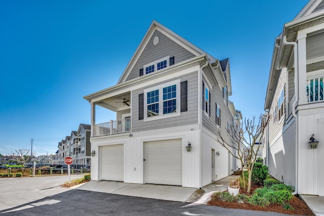 view of front of property featuring a balcony, driveway, an attached garage, and ceiling fan