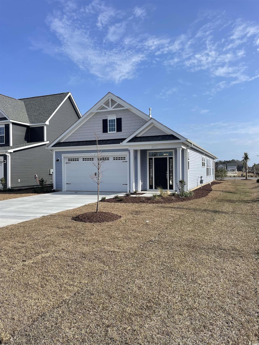 view of front of home with an attached garage, concrete driveway, and a front yard