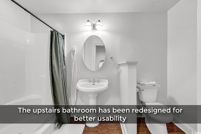 bathroom with hardwood / wood-style flooring, toilet, and walk in shower