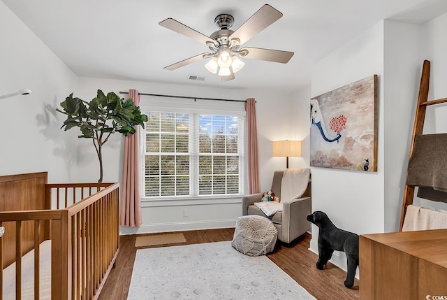 living area featuring dark wood-type flooring and ceiling fan