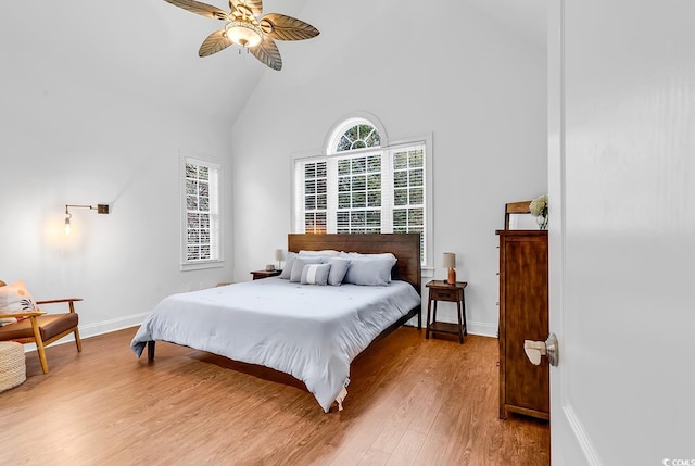 bedroom with ceiling fan, wood-type flooring, high vaulted ceiling, and multiple windows