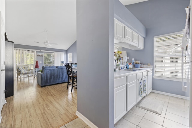 kitchen featuring ceiling fan, lofted ceiling, light tile patterned floors, and white cabinets