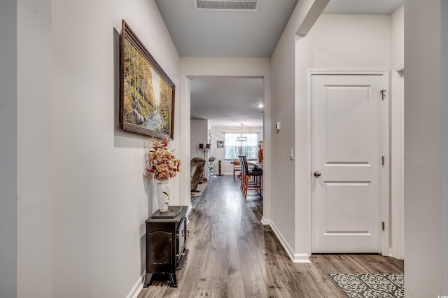 corridor with baseboards, visible vents, and wood finished floors