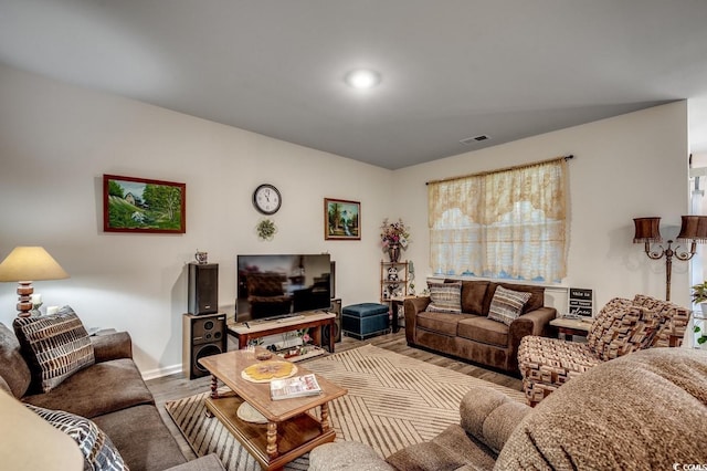 living room featuring visible vents, light wood-style flooring, and baseboards