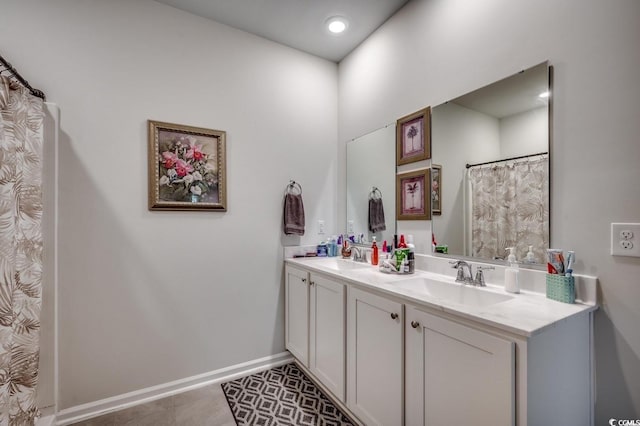 full bath featuring double vanity, tile patterned flooring, baseboards, and a sink