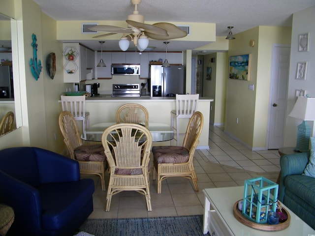 dining space with baseboards, visible vents, ceiling fan, a textured ceiling, and light tile patterned flooring