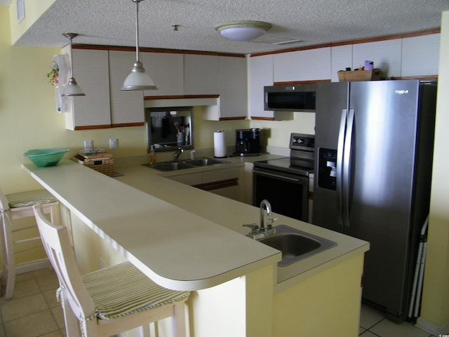 kitchen featuring stainless steel appliances, a peninsula, a sink, and light countertops