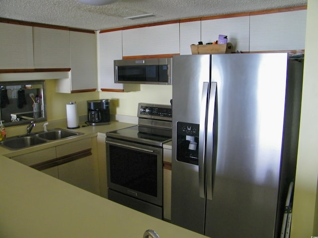 kitchen with visible vents, appliances with stainless steel finishes, light countertops, a textured ceiling, and a sink