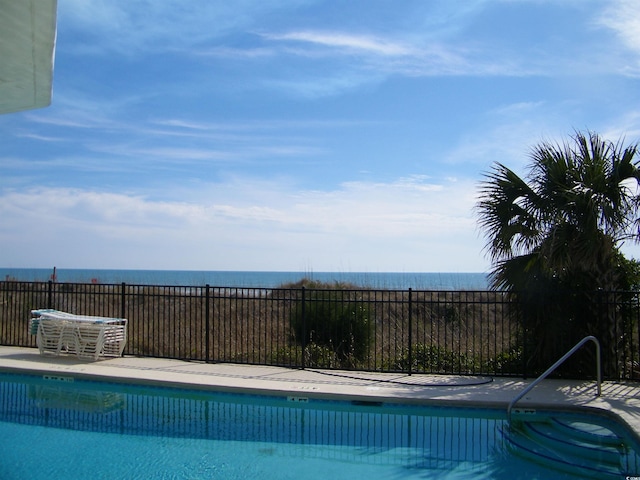 community pool featuring a water view and fence