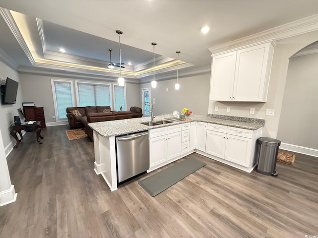 kitchen with arched walkways, a raised ceiling, a sink, dishwasher, and a peninsula