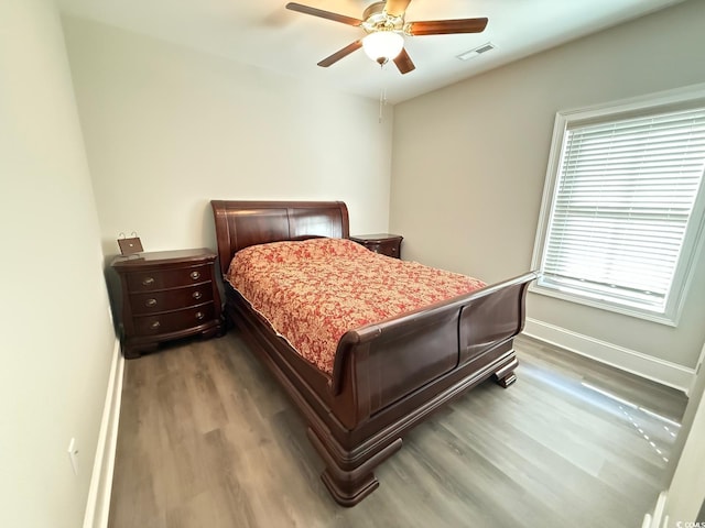 bedroom with a ceiling fan, baseboards, visible vents, and wood finished floors