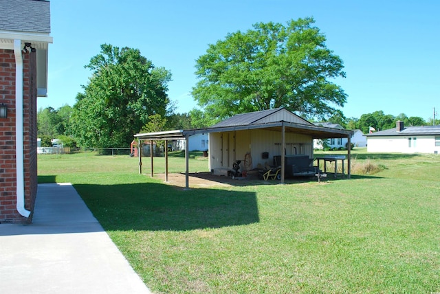 view of yard featuring a carport, fence, and driveway