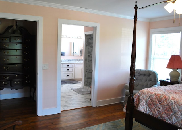 bedroom featuring connected bathroom, a sink, baseboards, dark wood finished floors, and crown molding