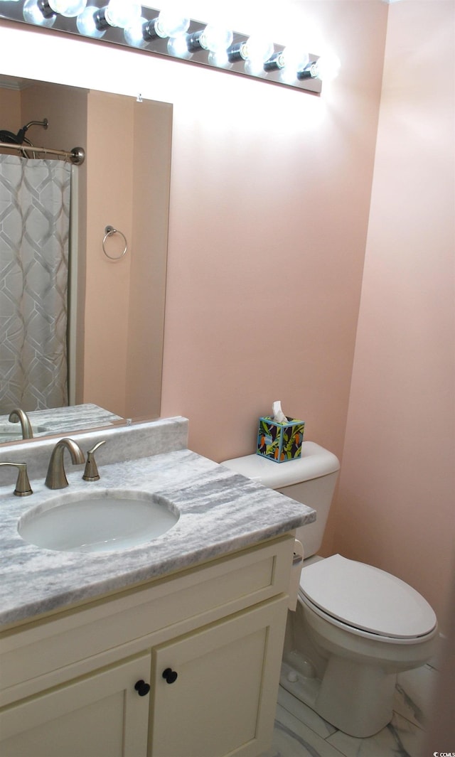 bathroom with toilet, marble finish floor, and vanity