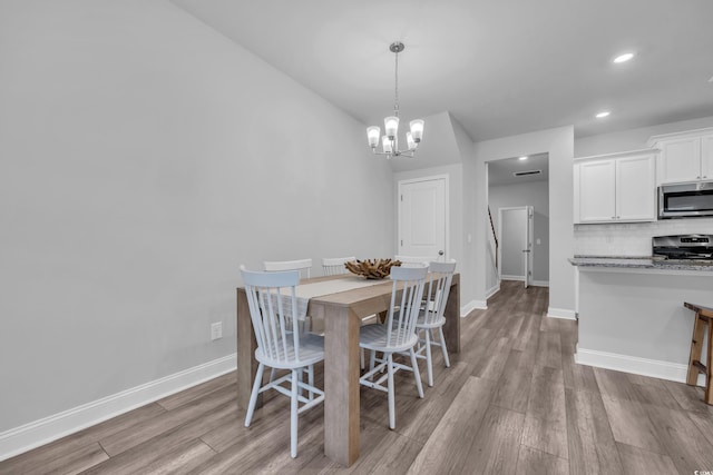 dining space with an inviting chandelier and light hardwood / wood-style floors