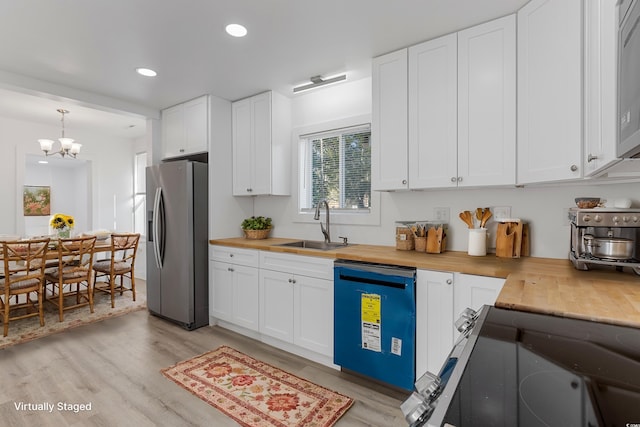 kitchen featuring a sink, wood counters, white cabinetry, appliances with stainless steel finishes, and pendant lighting