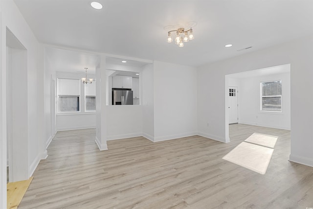 unfurnished living room with an inviting chandelier, light wood-style flooring, and recessed lighting