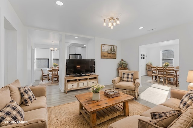 living area with light wood-style floors, recessed lighting, and an inviting chandelier