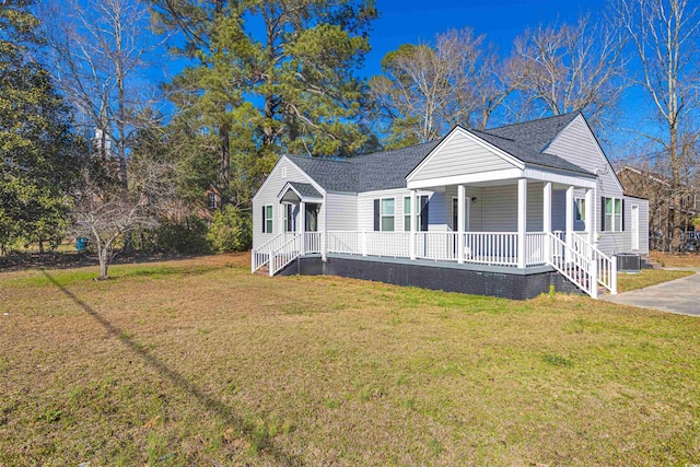 view of front facade featuring a shingled roof, a porch, cooling unit, and a front yard