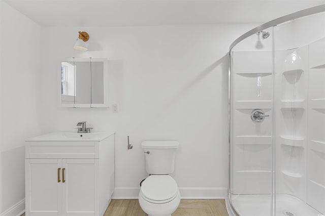 bathroom with toilet, wood finished floors, vanity, baseboards, and a shower stall