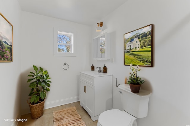 bathroom featuring toilet, wood finished floors, vanity, and baseboards