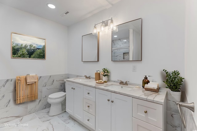 bathroom featuring marble finish floor, a sink, toilet, and double vanity