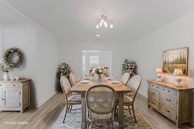 dining space with light wood-type flooring, baseboards, and a notable chandelier