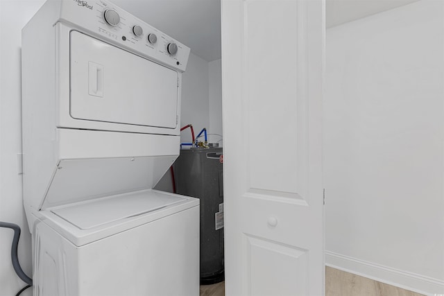 washroom featuring light wood finished floors, stacked washer and dryer, electric water heater, laundry area, and baseboards