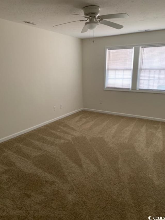 carpeted spare room with ceiling fan, a textured ceiling, and baseboards